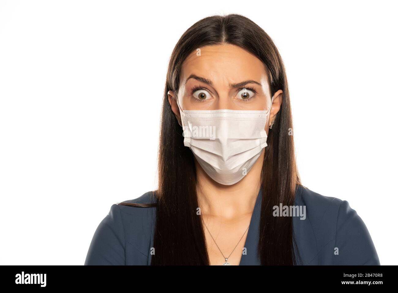 Schöne überraschte Frau mit Schutzmaske auf ihrem Gesicht auf weißem Hintergrund Stockfoto