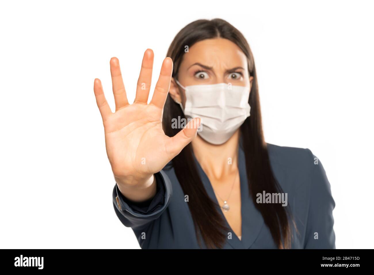 Wütende Frau mit Stopphand und Schutzmaske auf ihrem Gesicht auf weißem Hintergrund Stockfoto