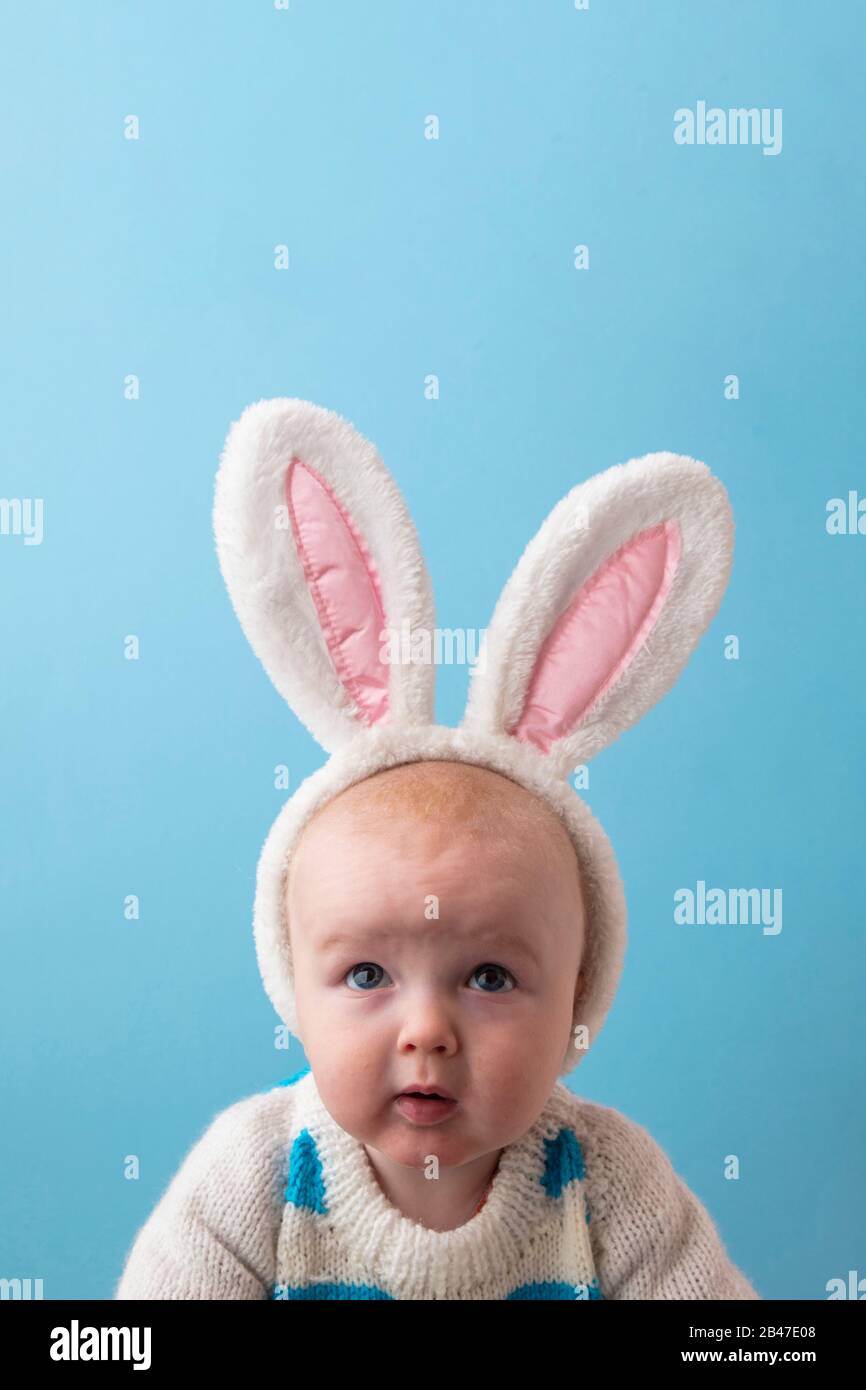 Süßes kleines Baby mit weißen easter Hunny Ohren vor blauem Hintergrund Stockfoto