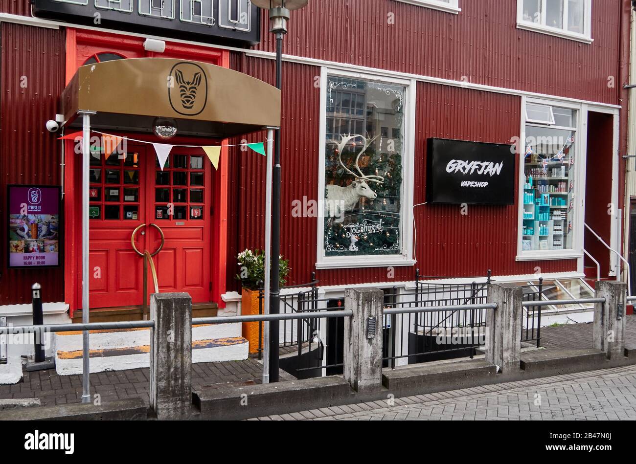 Europa, Reykjavik, Island, Ingolfstorg-Platz, Geschäfte und Restaurants in langen roten Häusern an einem regnerischen Tag im Sommer Stockfoto
