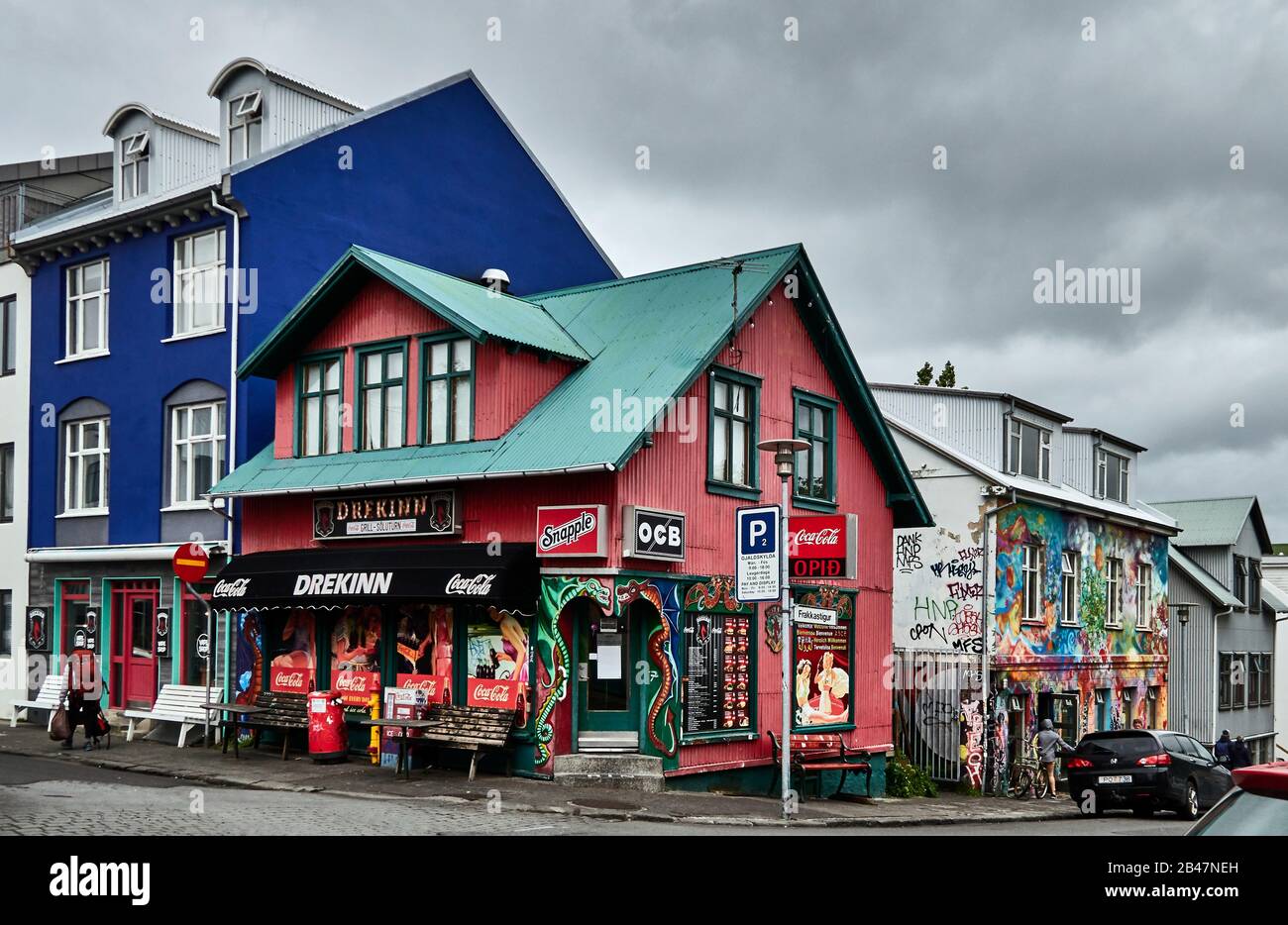 Europa, Frakkastigur Straße, Leute, die an einem regnerischen Tag im Sommer in der Altstadt von Reykjavik, Island, entlang von Geschäften und Restaurants laufen. Stockfoto