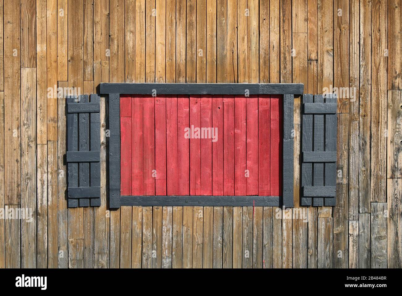 Ein helles rotes geendetes Schaufenster mit Fensterläden Stockfoto