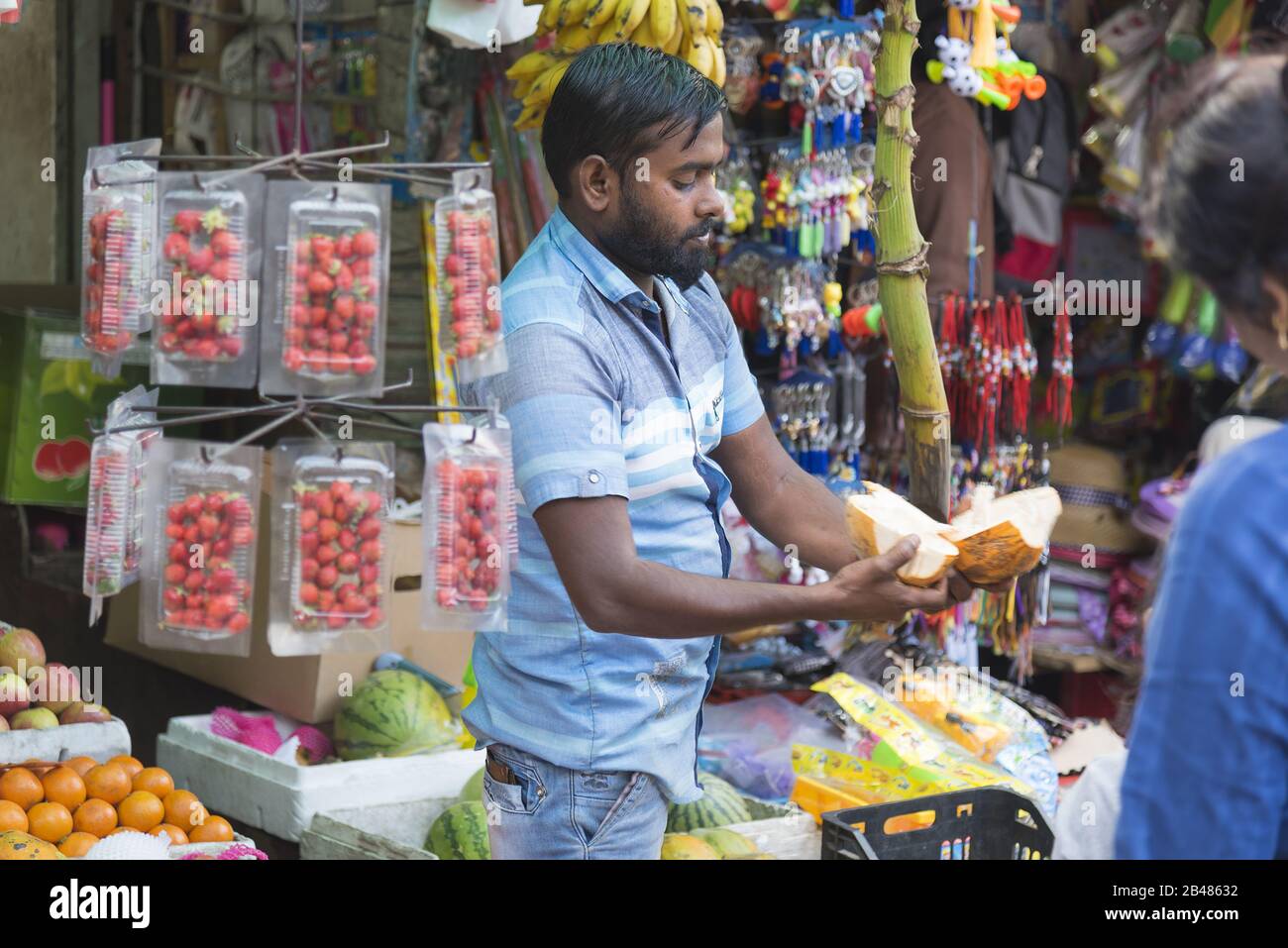 Nuwara Eliya, Sri Lanka: 20.03.2019: Traditionelles Obst- und Veg-Geschäft, Mann bereitet Kokosnuss vor. Stockfoto