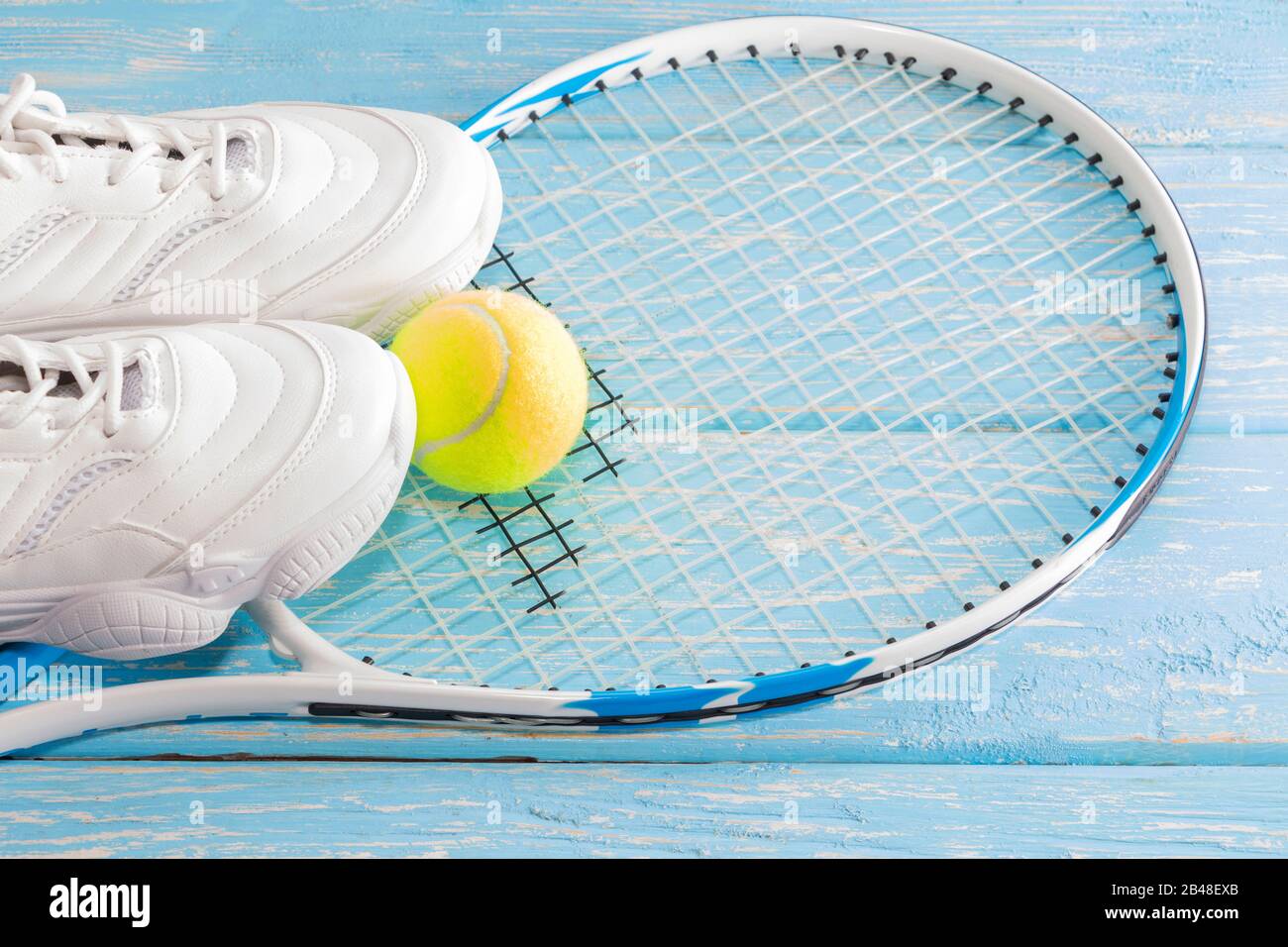 Tennisschläger mit Ball und Turnschuhen, auf hellem Hintergrund. Fotografiert im Studio Stockfoto