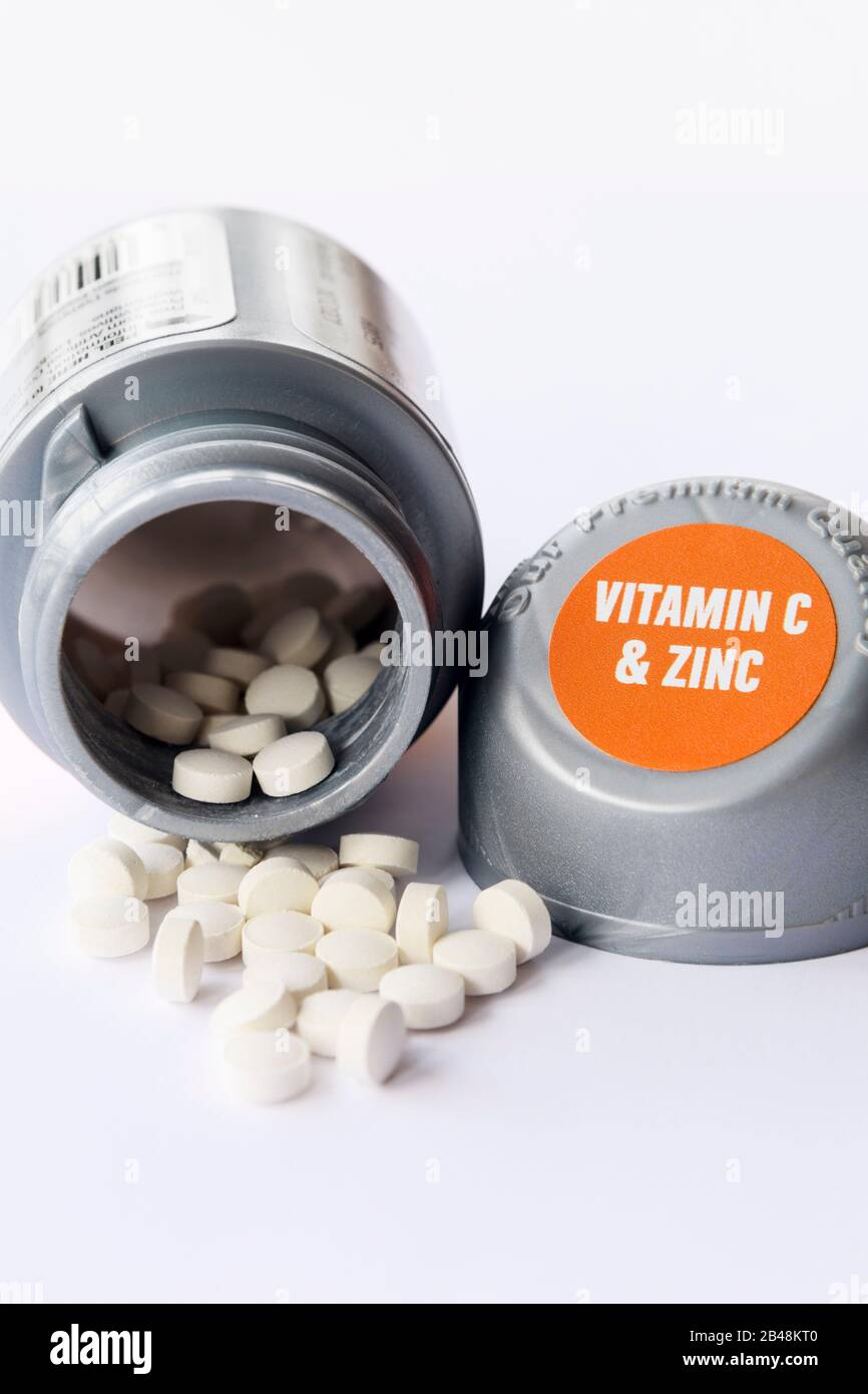 Pillen, die aus einer Flasche Vitamin C und Zink-Ergänzungstabletten zur Stärkung des Immunsystems verschüttet werden Stockfoto