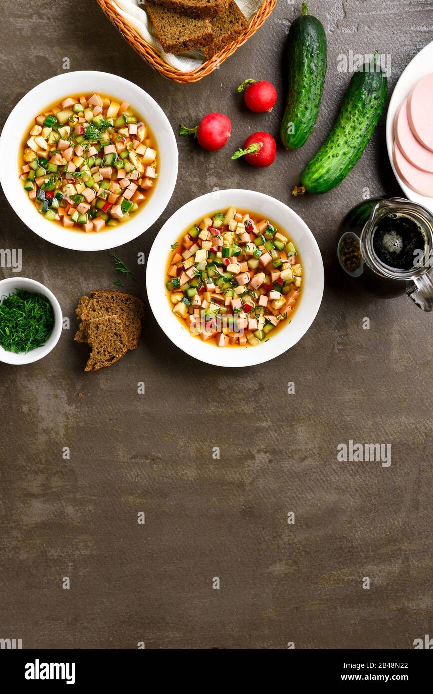 Kalte russische Suppe Okroschka mit Wurst, Gemüse und Kvass über braunem Steinhintergrund mit freiem Textraum. Leckeres Sommergericht zum Abendessen. Draufsicht Stockfoto
