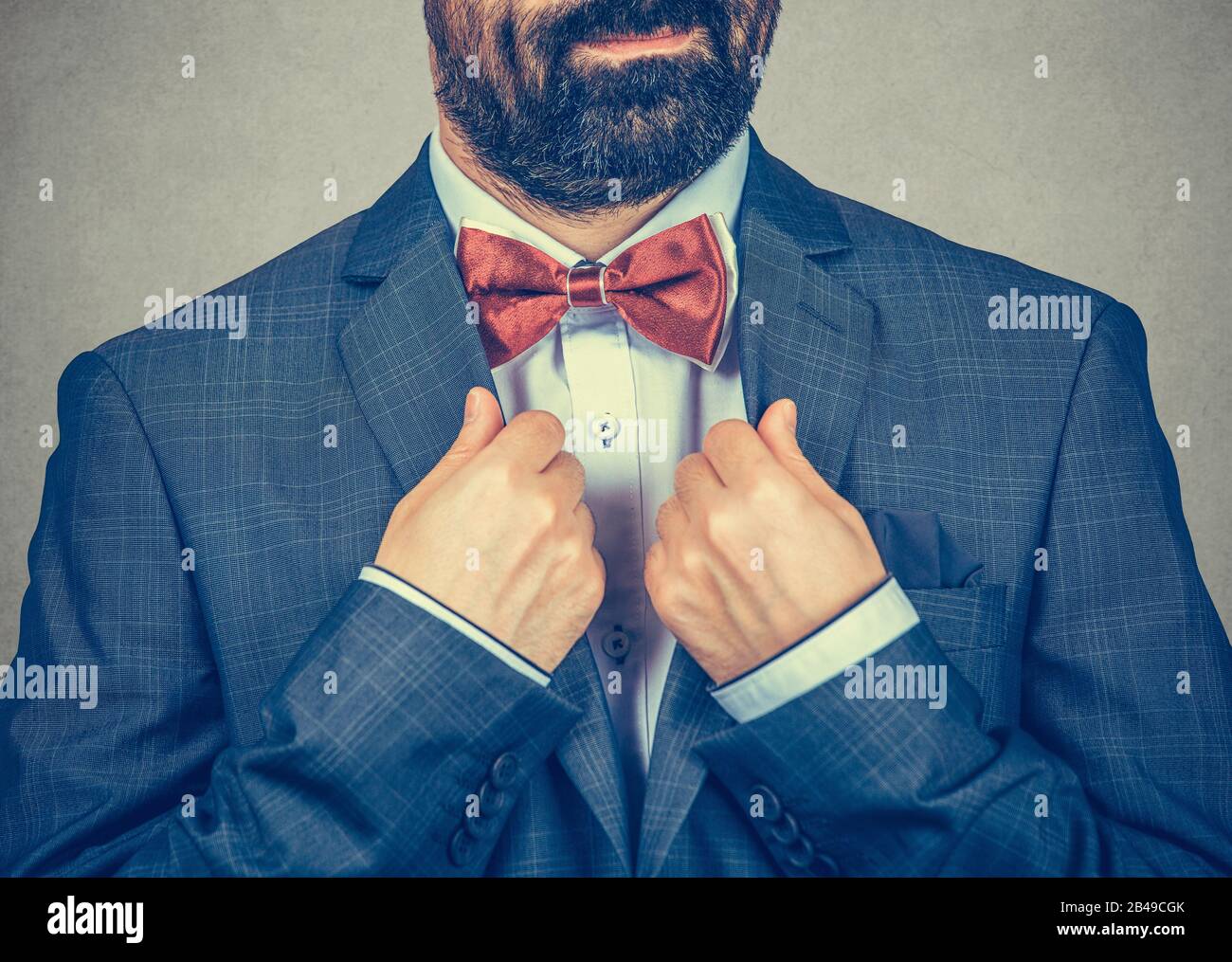 Zuschnitt junger Bräutigam in klassigem schwarzen Anzug mit weißem knöpftem Hemd, das die rote Krawatte verstellt. Hochzeitsvorbereitungen. Nahaufnahme Porträt von Mixed Race Be Stockfoto