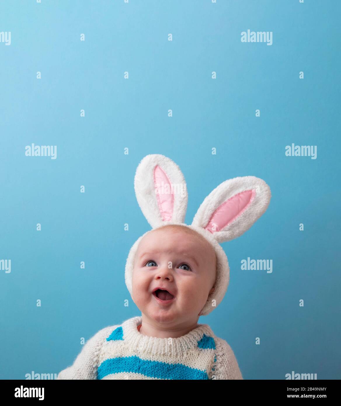 Süßes kleines Baby mit weißen easter Hunny Ohren vor blauem Hintergrund Stockfoto