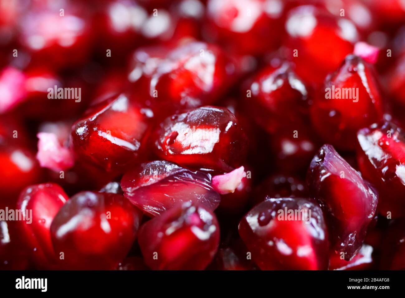 Makro-Vollbild-Nahaufnahme von rot glänzenden, saftigen Granatapfelsamen (Fokus auf Mitte) Stockfoto