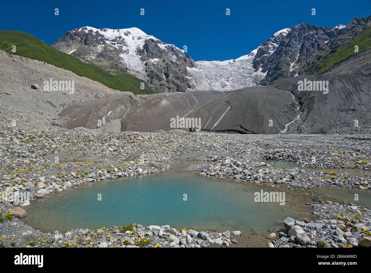 Berglandschaft. Großer Gletscher vor blauem Himmelshintergrund. Kleiner See (Vordergrund) am Fuß des Eisfalles. Stockfoto