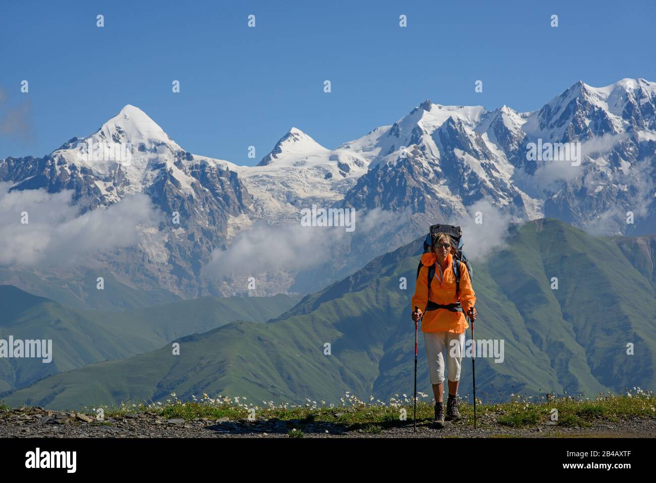Tourist vor Hochgebirge Hintergrund. Frau liegt auf der Alpenwiese. Stockfoto