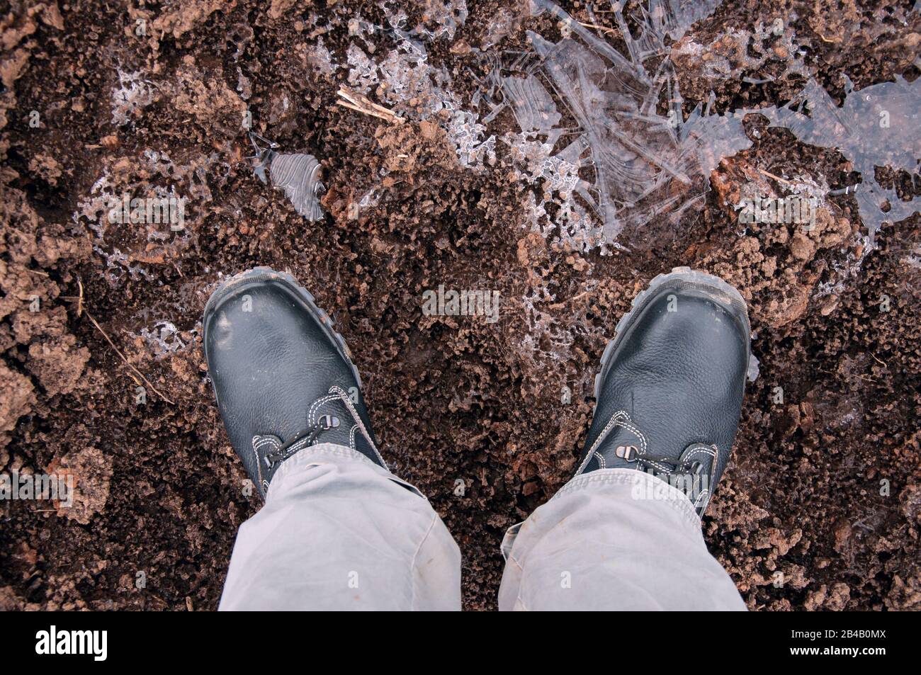 Schwarze Arbeitsstiefel auf eisbedecktem Boden. Arbeitsschuhe für die Arbeit. Stockfoto