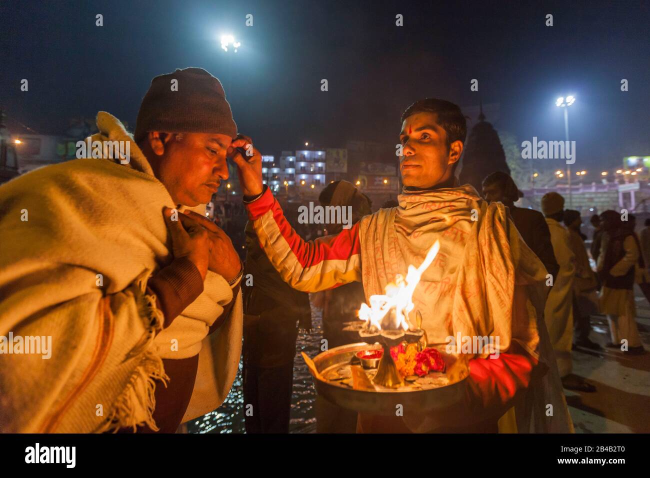 Indien, Uttarakhand, Haridwar, heilige Stadt des hinduismus, Kumbh Mela Hindu-Pilgerreise, Har Ki Pauri Ghat, heiliger Mann segnet Pilger nach aarti, Abendgebet Stockfoto