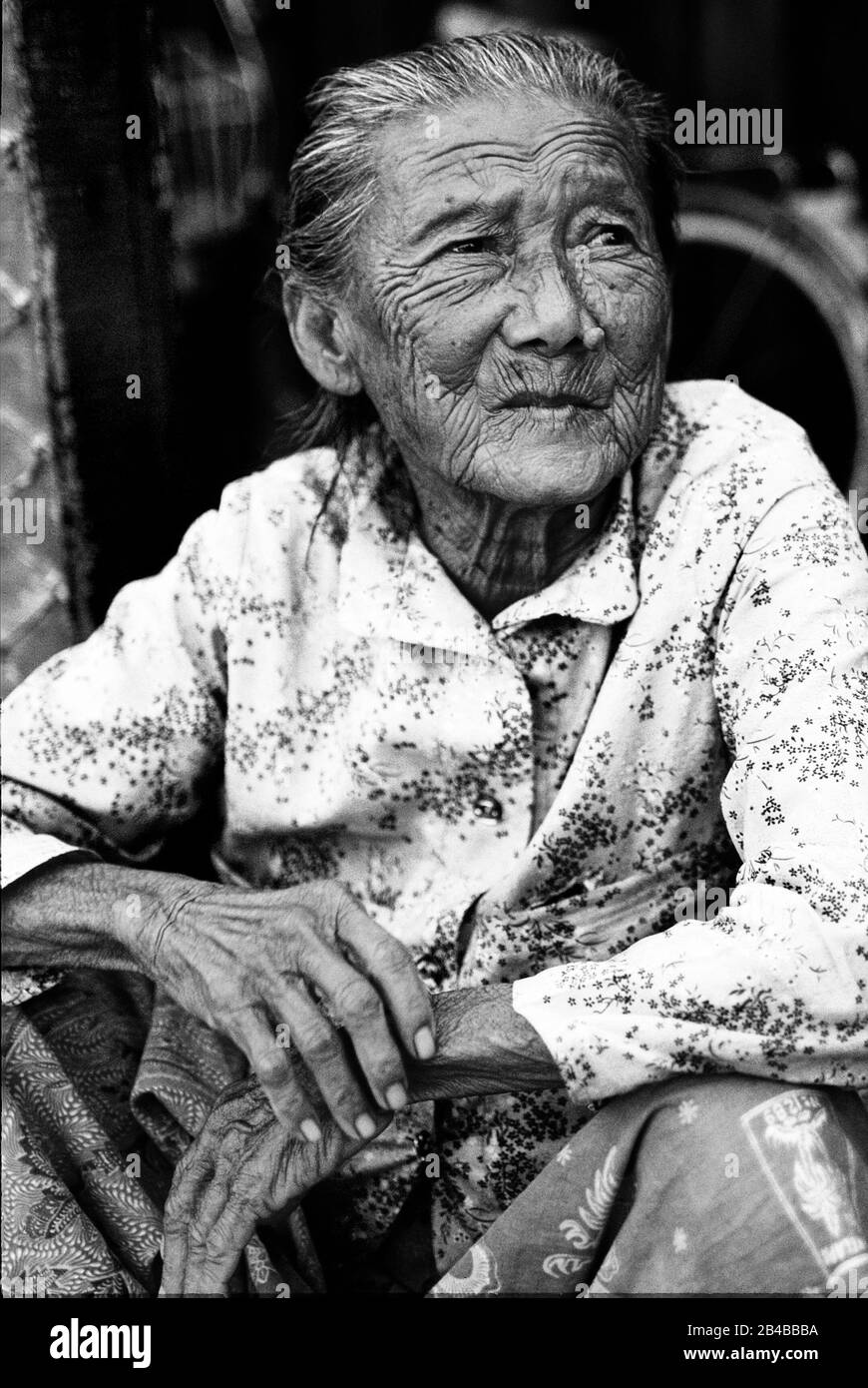 Porträt einer charaktervollen alten Dame mit geknitterten Händen und Gesicht, mit einem Sarong in George Town, Penang, Malaysia. Stockfoto