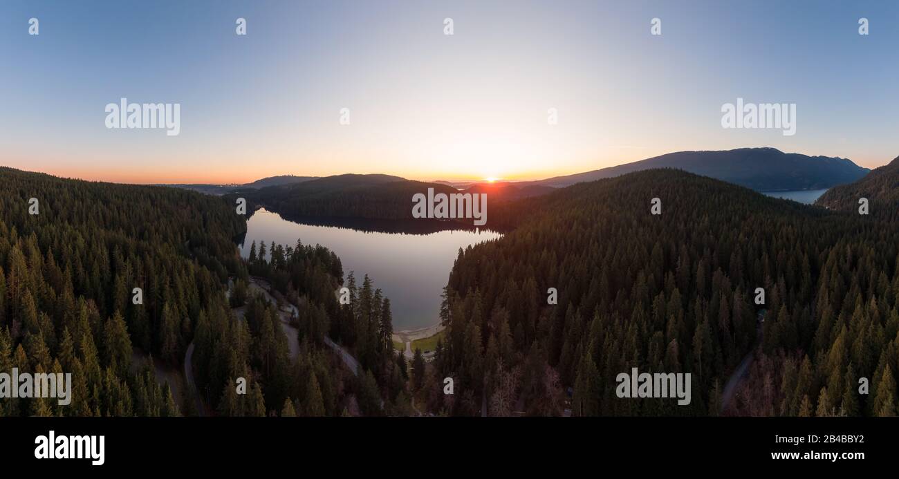 Wunderschöner und Lebendiger Panoramablick auf einen See, der bei Sonnenuntergang von der kanadischen Berglandschaft überragt wird. Aufgenommen in White Pine Beach, Port Moody, V. Stockfoto