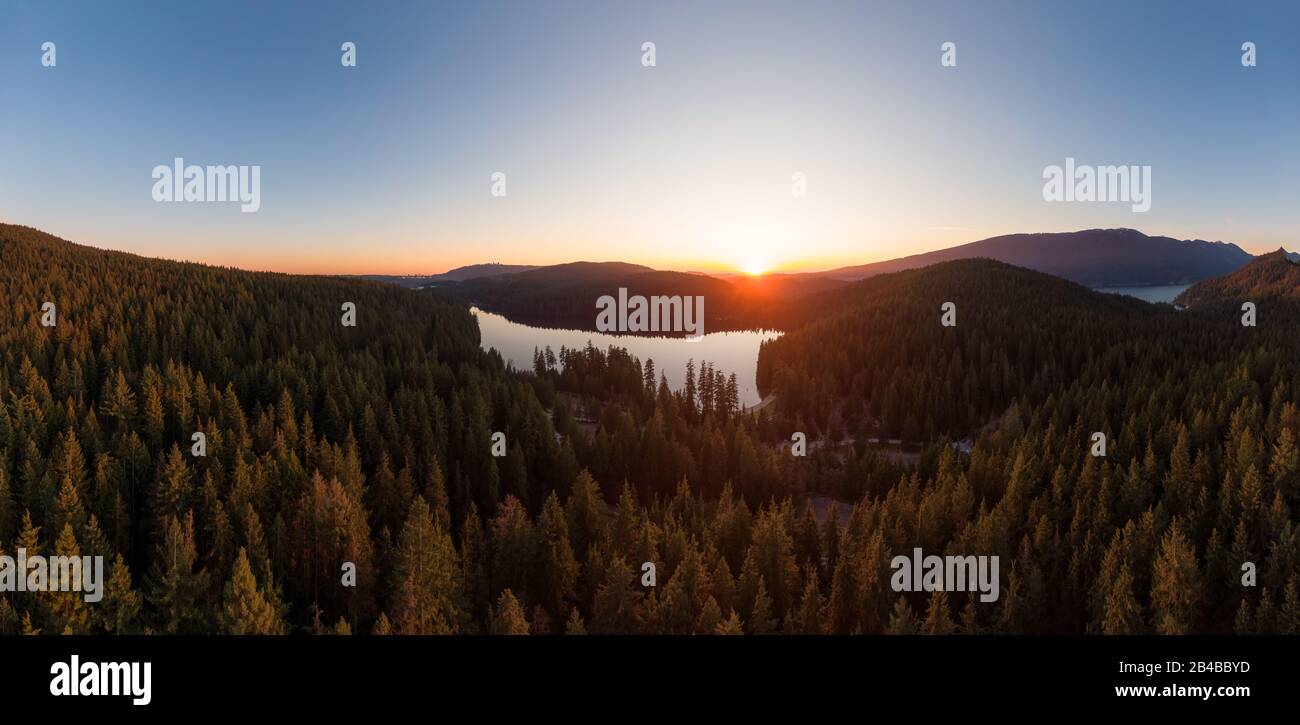 Wunderschöner und Lebendiger Panoramablick auf einen See, der bei Sonnenuntergang von der kanadischen Berglandschaft überragt wird. Aufgenommen in White Pine Beach, Port Moody, V. Stockfoto