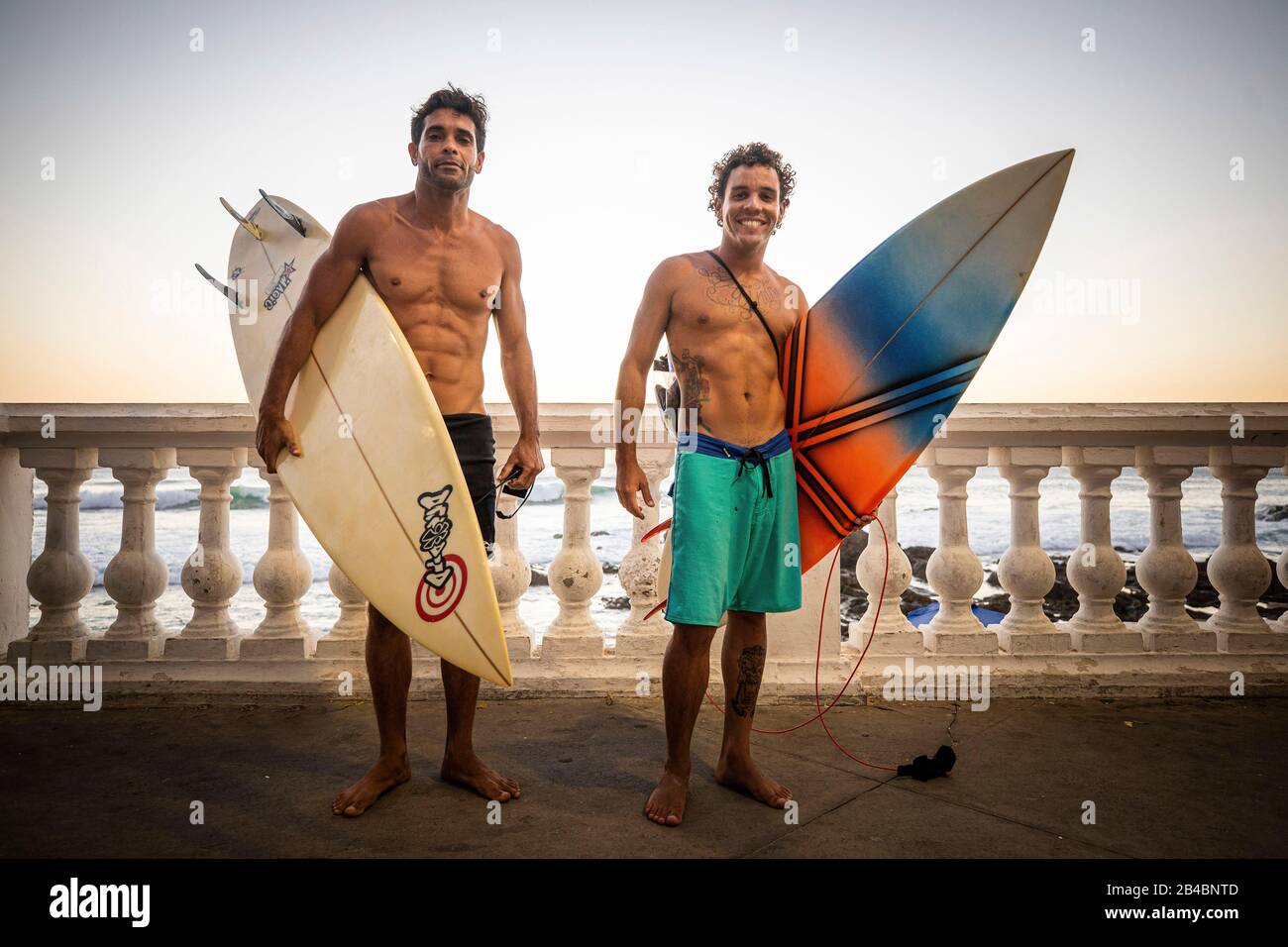 Brasilien, Bundesstaat Bahia, Salvador de Bahia, am Meer am Ende des Tages posieren zwei Surfer Stockfoto