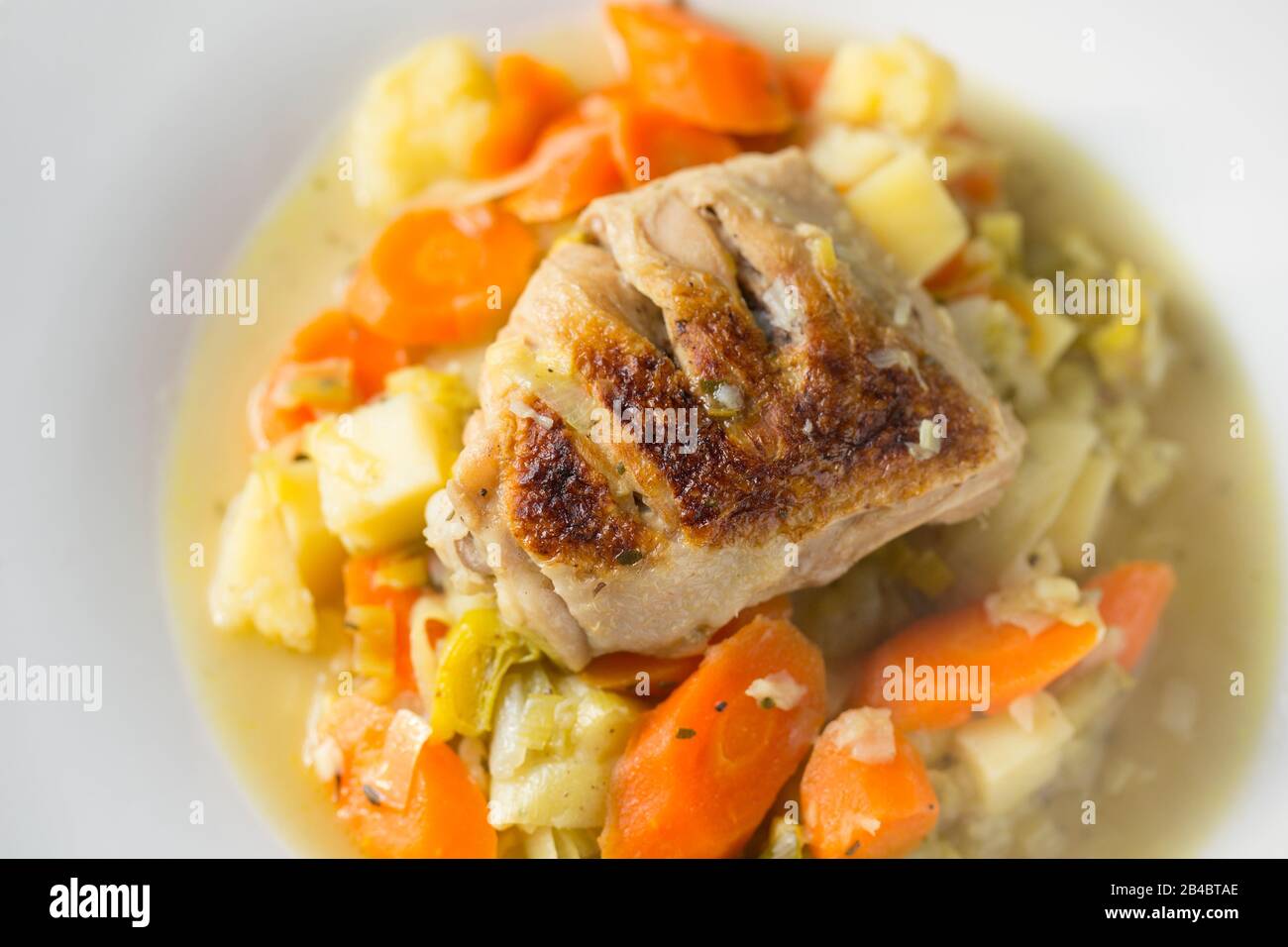 Ein Hühnerschenkel kaufte sich von einem Supermarkt, der auf einem George Foreman-Fettreduzierungsgrill gegrillt wurde, bevor er mit Karotten, Lauch, Zwiebeln gedünstet wurde Stockfoto