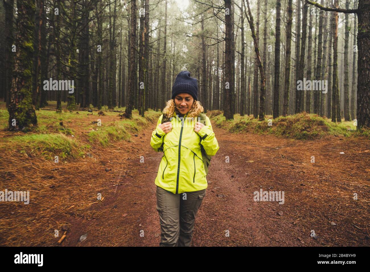 Fröhliche Wanderer reisen in den hohen Bäumen wilder schöner Wald mit Rucksack - Naturholz für hübsche blonde junge Frau genießen - Abenteuer- und Trekkking-Konzept Stockfoto