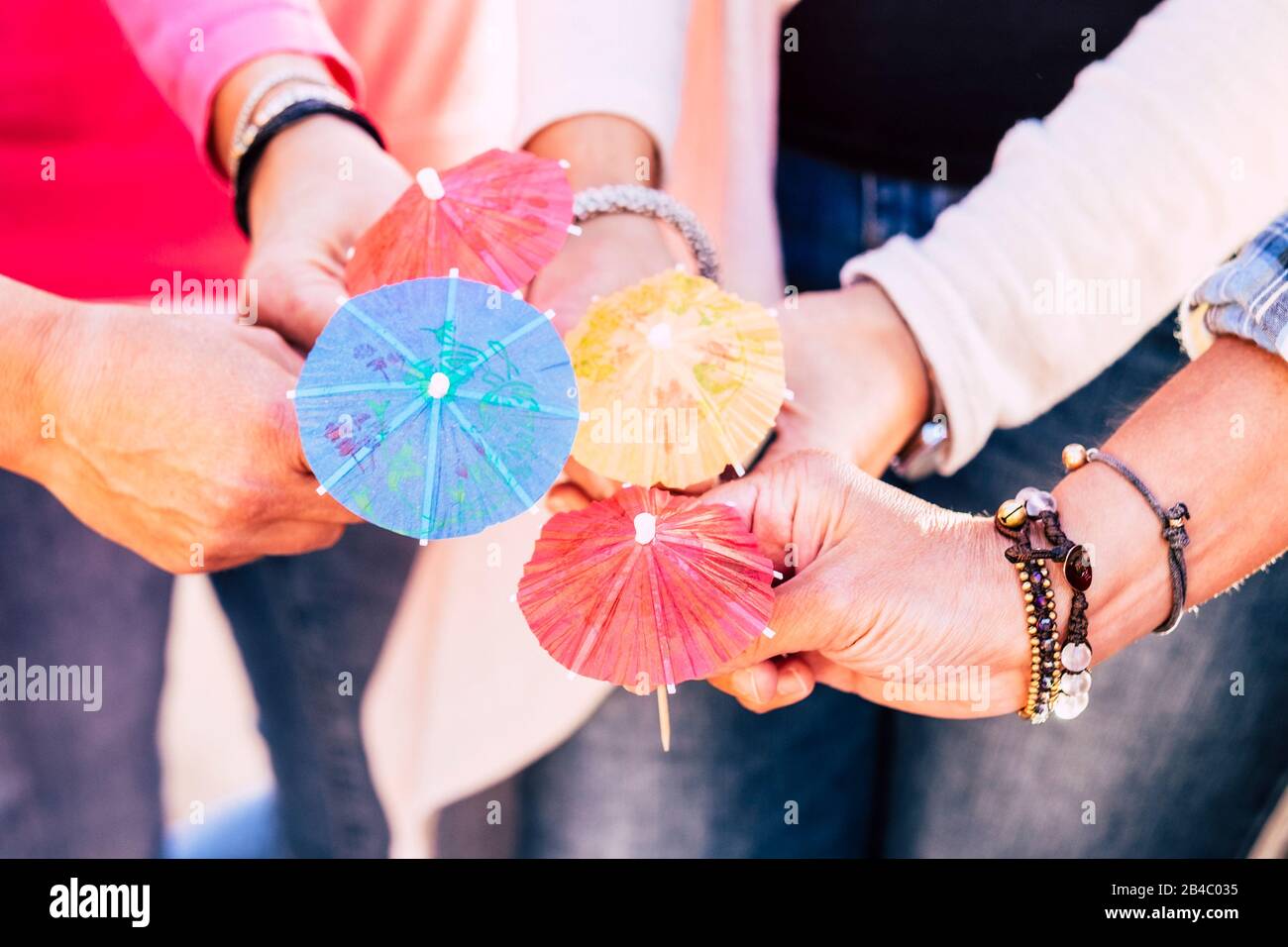 Nahaufnahme mit einer Gruppe von Menschen halten und vier cocktail Schirme zusammen angezeigt - Freundschaft und Zusammenarbeit im Team feiern Konzept Lebensstil Stockfoto
