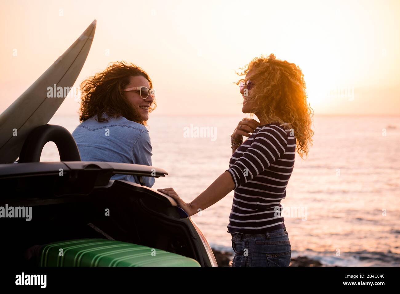 Schöne Leute Paar Freunde lockige Dame, die gemeinsam Reisen genießt und Spaß mit dem Sonnenuntergang auf dem Meer hat - Sommerferienferienkonzept mit glücklichen Weibchen und Auto und Luggagen Stockfoto Schöne Leute Paar Freunde lockige Dame, die gemeinsam Reisen genießt und Spaß mit dem Sonnenuntergang auf dem Meer hat - Sommerferienferienkonzept mit glücklichen Weibchen und Auto und Luggagen Stockfoto