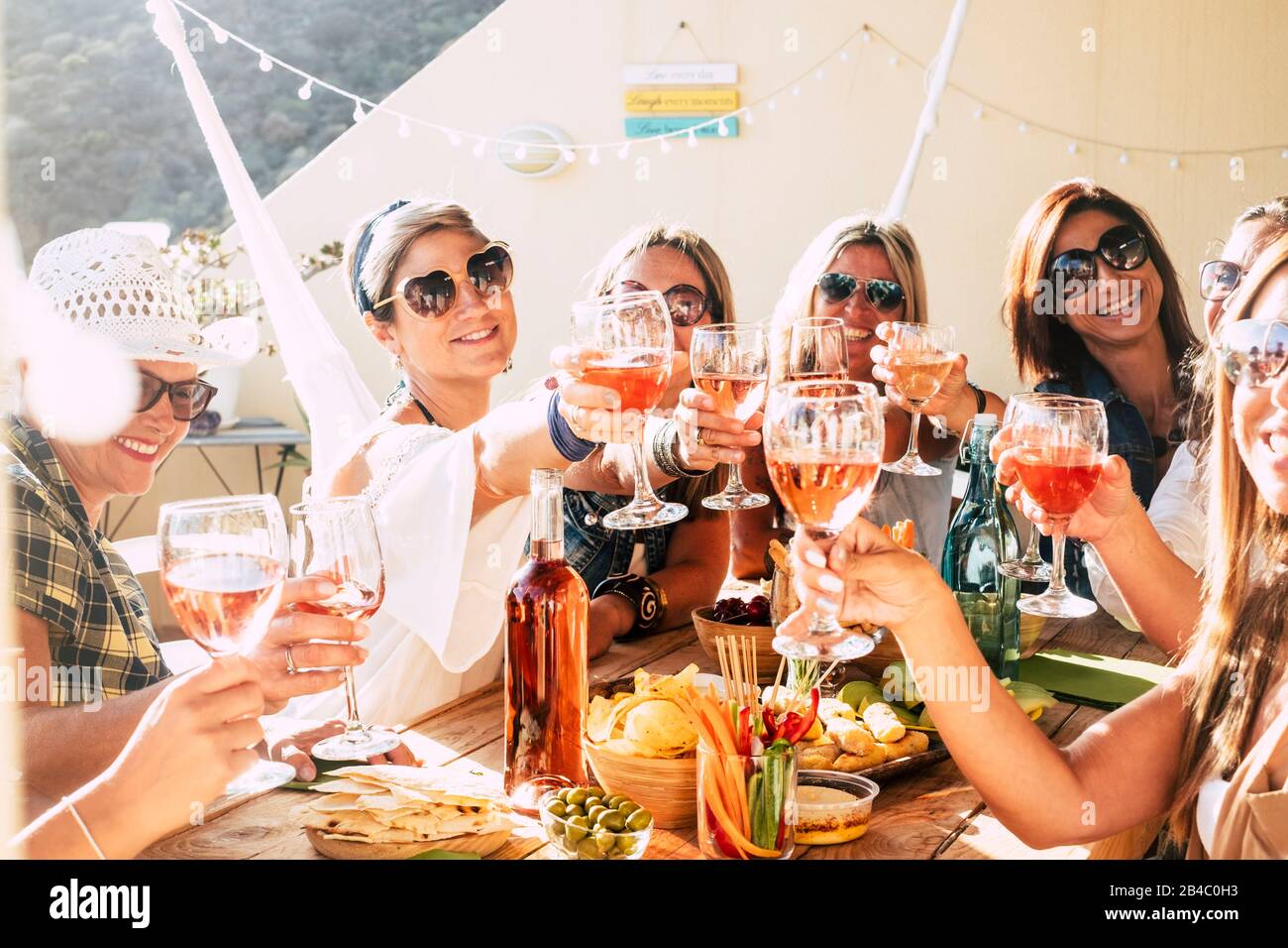 Fröhliche Gruppe glücklicher Frauen, die sich mit Freundschaft und Glück zusammenklattern und toasten - junge und Erwachsene Frauen haben Spaß am Essen - Konzept der Speise- und Getränkefeier Stockfoto