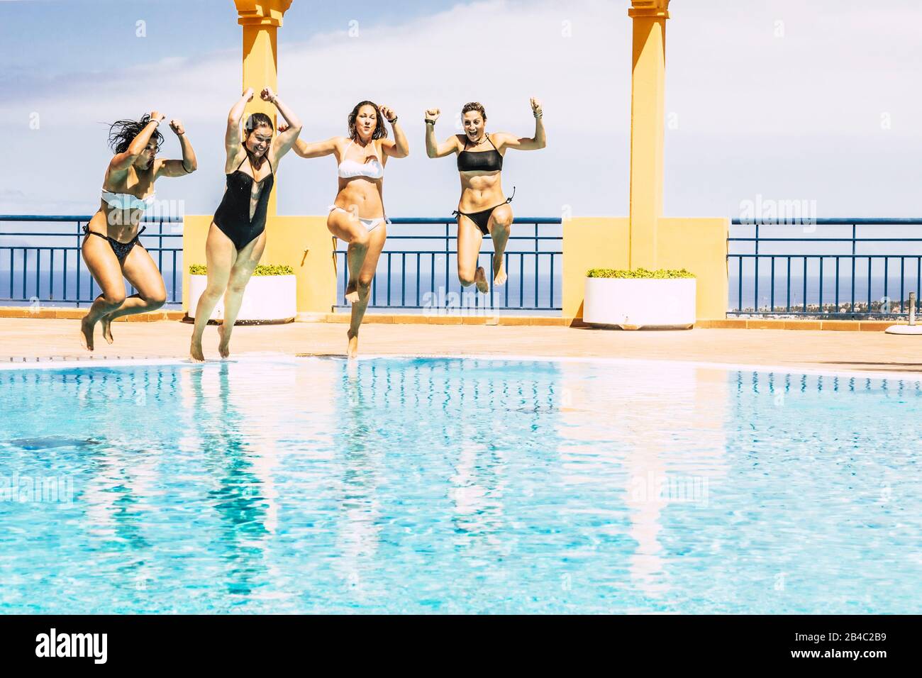 Jugendliche fröhliche junge Leute springen zusammen im Schwimmbad und genießen die Sommerurlaub Vaction Saison - Freunde hazen Spaß im Freien mit blauem Wasser und Urlaub Lifestyle Stockfoto