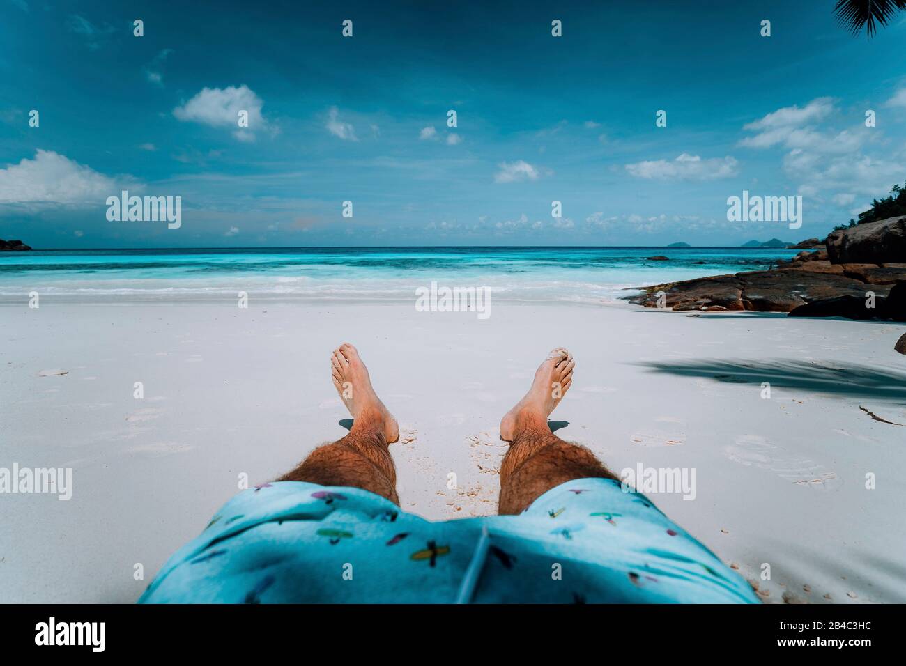 Urlaub Hintergrund männliche Beine mit Schwimmen kurz am Paradies weißer Sand tropischer Strand vor türkisfarbenem Meer. Exotische Feiertage. Stockfoto