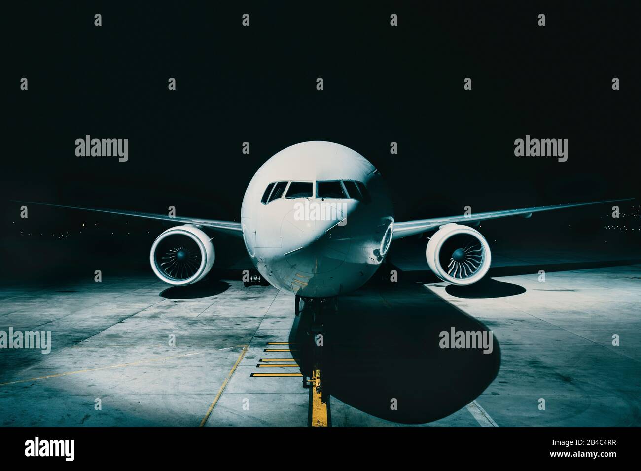 Flieger-Flugzeug am Terminal geparkt vom vorderen Cockpit-Rumpf, nachts auf der Landebahn. Stockfoto