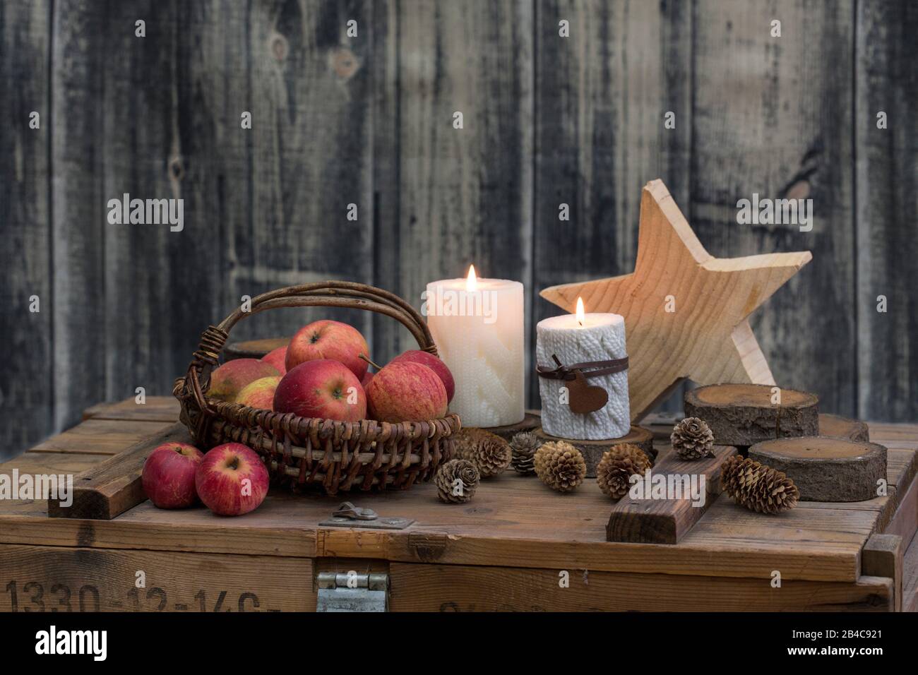 Rustikaler still Life Hyggge-Stil mit Holzsternen, Äpfeln und Kerzen auf alten Kisten Stockfoto
