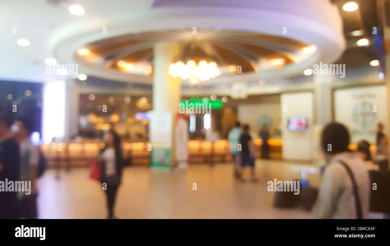 Verschwommener Hintergrund der zentralen Halle des Einkaufszentrums mit Menschen, die in geschäftiger Umgebung laufen und einkaufen Stockfoto