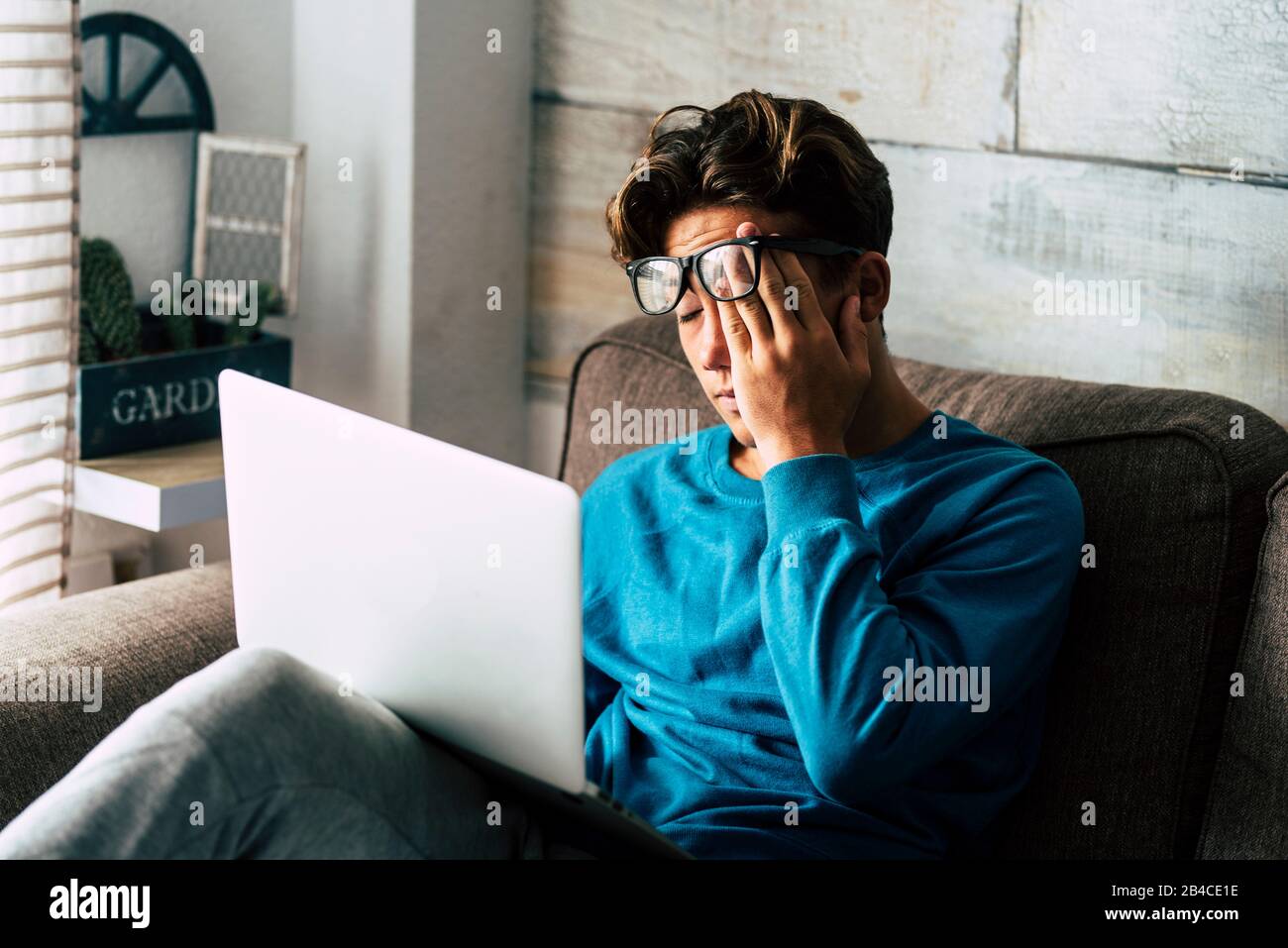 Gestresster Schüler zu Hause, der mit einem persönlichen Laptop studiert - müde Teenager für die Schularbeit - Internet. Sucht nach Spiel- oder Jobsuchkonzept - Technik im Innenbereich Stockfoto