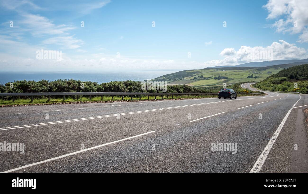 Scottish Highland Road Trip. Eine ruhige Küstenstraße, die an einem hellen Sommertag durch die schottischen Highlands führt. Stockfoto