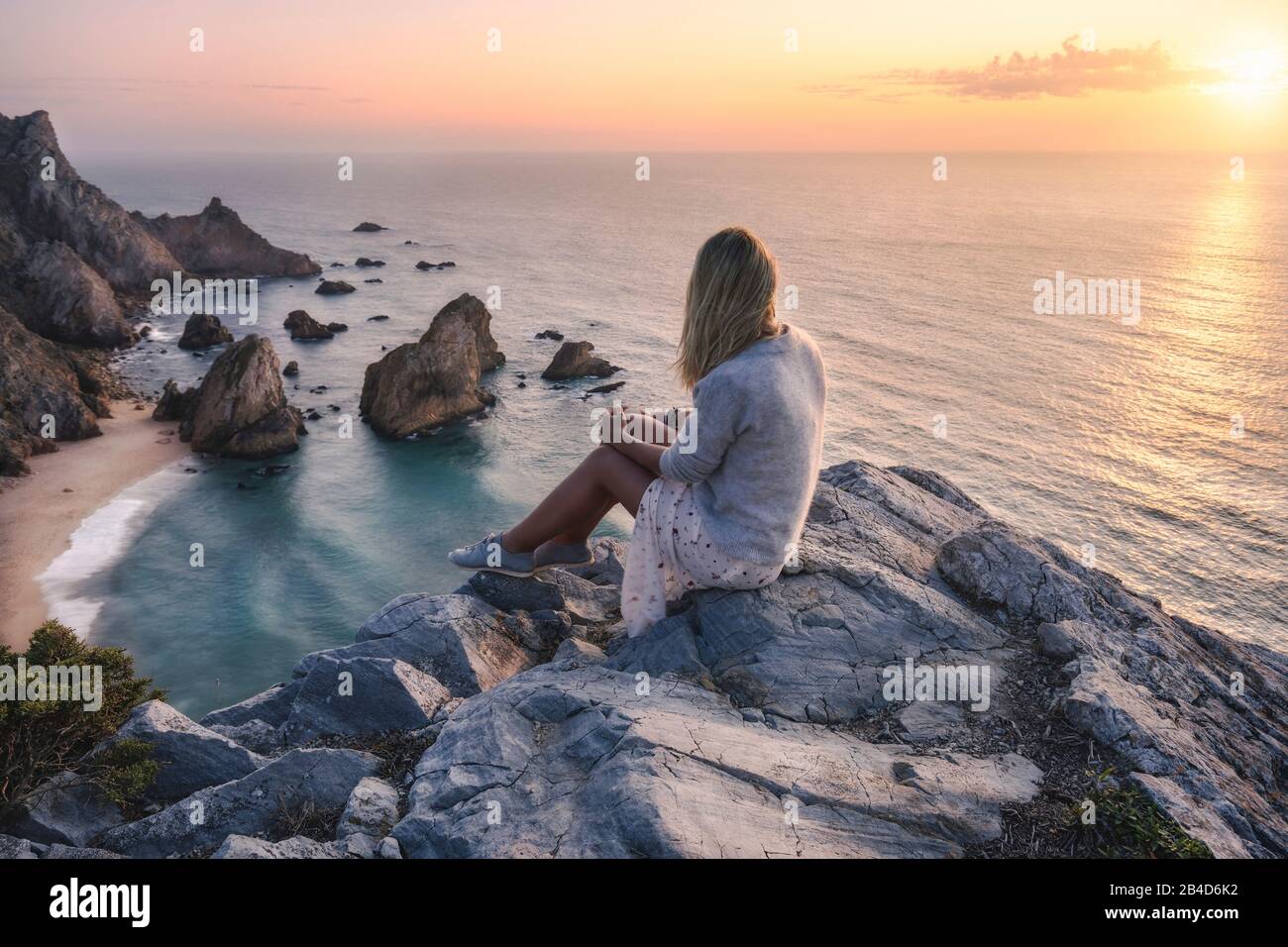 Schöne Touristenfrauen, die den Sonnenuntergang am Strand Praia da Ursa genießen. Surreale Landschaft von Sintra, Portugal. Küstenlandschaft am Atlantik. Stockfoto