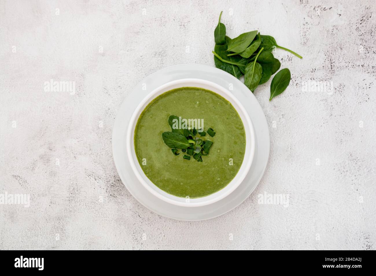 Gesunde Ernährung. Cremige Spinatsuppe mit Spinat auf hellem Hintergrund. Frühlingsnahrung, Ernährungskonzept. Stockfoto