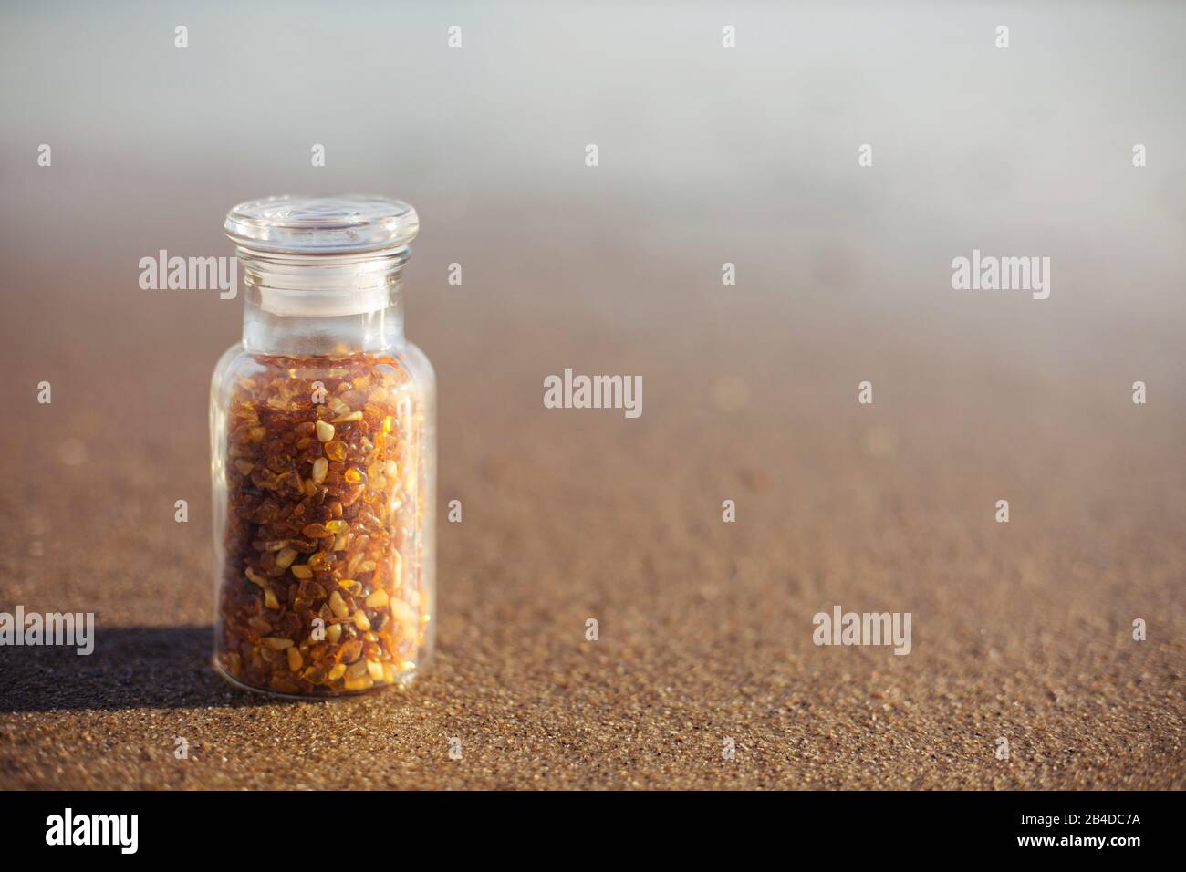 Glas mit polierten Ambern am Strand Stockfoto