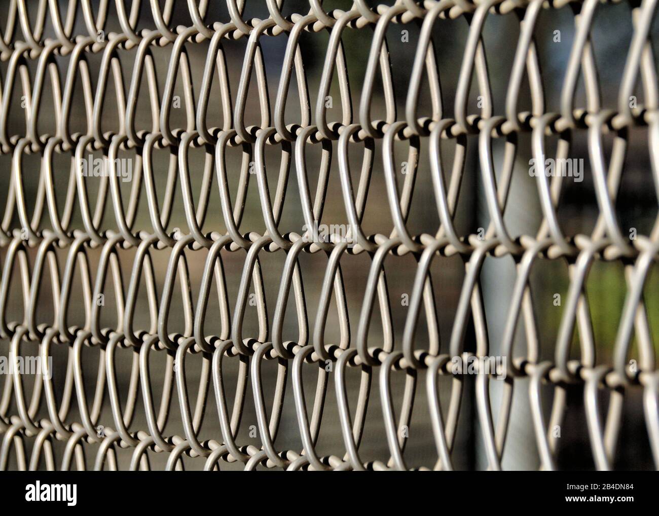 Eine Nahansicht der Metallverbindungen eines Kettengliederzauns macht ein attraktives abstraktes Muster. Stockfoto