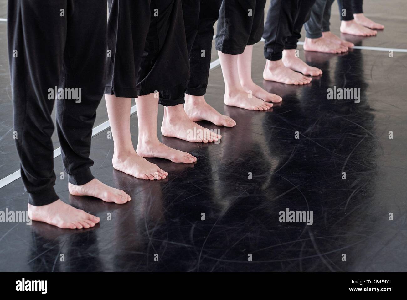 Beinreihe von barfuß-jungen Tänzern in schwarzen Hosen, die auf dem Boden des Tanzstudios stehen, während sie beim Training trainieren Stockfoto
