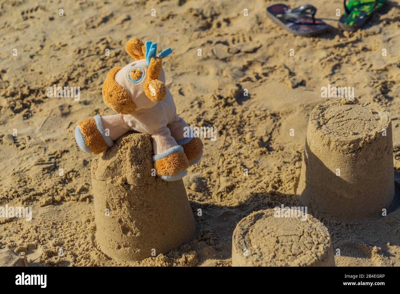 Auf einer Sandburg sitzt ein gestopftes Tier eines Kindes Stockfoto