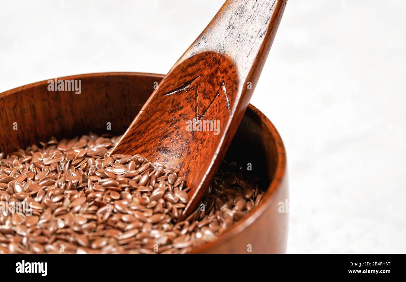 Gemeinsame Flachs Lein - Linum usitatissimum - kleine hölzerne Schüssel, closeup auf Holzlöffel in Haufen Samen. Stockfoto