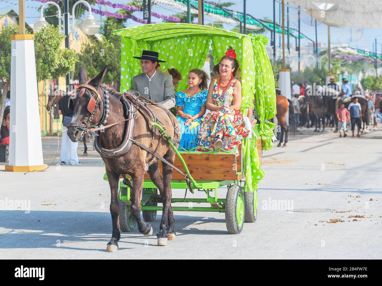 Menschen, die traditionelle Kleider tragen, die auf einer Kutsche fahren, Malaga Festival, Málaga, Andalusien, Spanien, Stockfoto