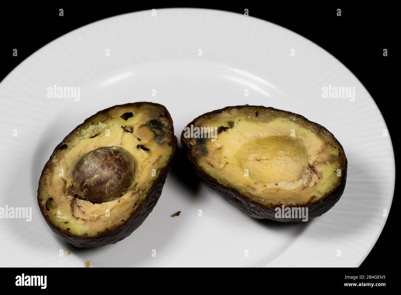 Avocados verfaulten Lebensmittel auf weißem Teller. Verdorbene und zerquetschte Lebensmittel, die nicht gegessen werden können. Überreife Avocados verschwendeten Nahrung. Stockfoto