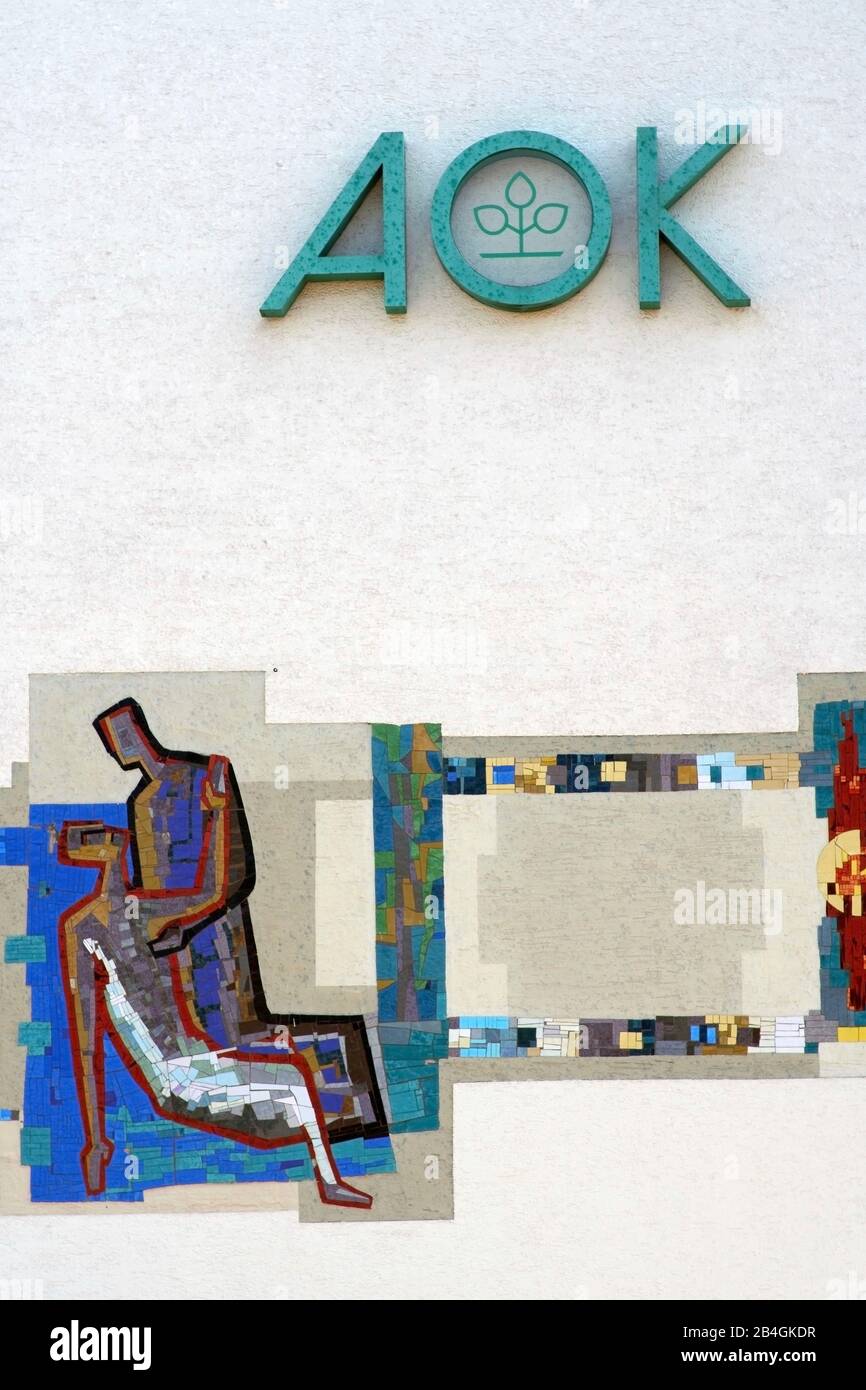 Das Logo der Krankenkasse AOK an der Fassade eines Büro- und Geschäftshauses mit Mosaikgemälde in Alzenau. Stockfoto