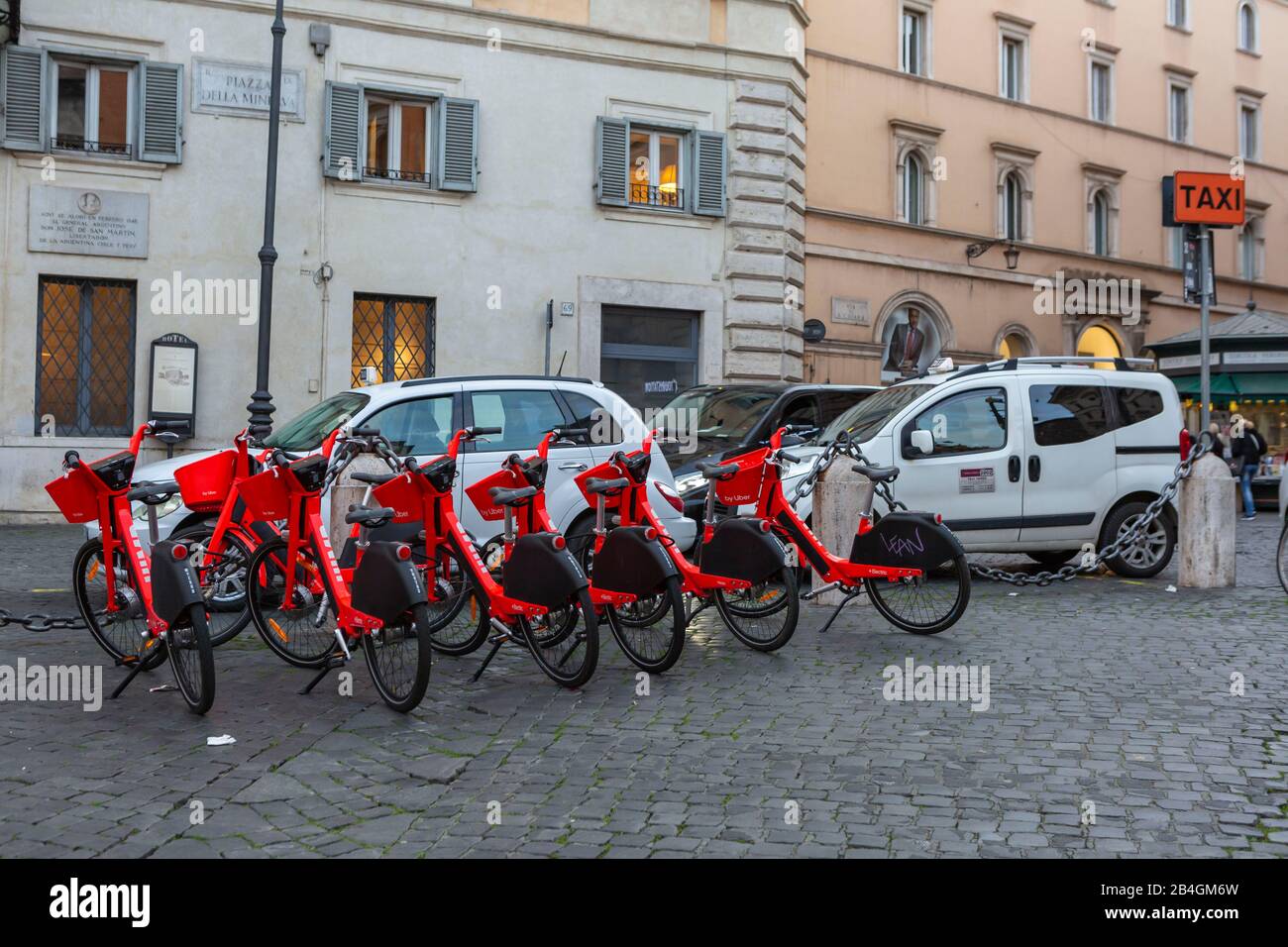 Neben Taxis, die auf einer Piazza in Rom auf Passagiere warteten, reihte sich eine Reihe von Uber Jump Elektrorädern ein Stockfoto