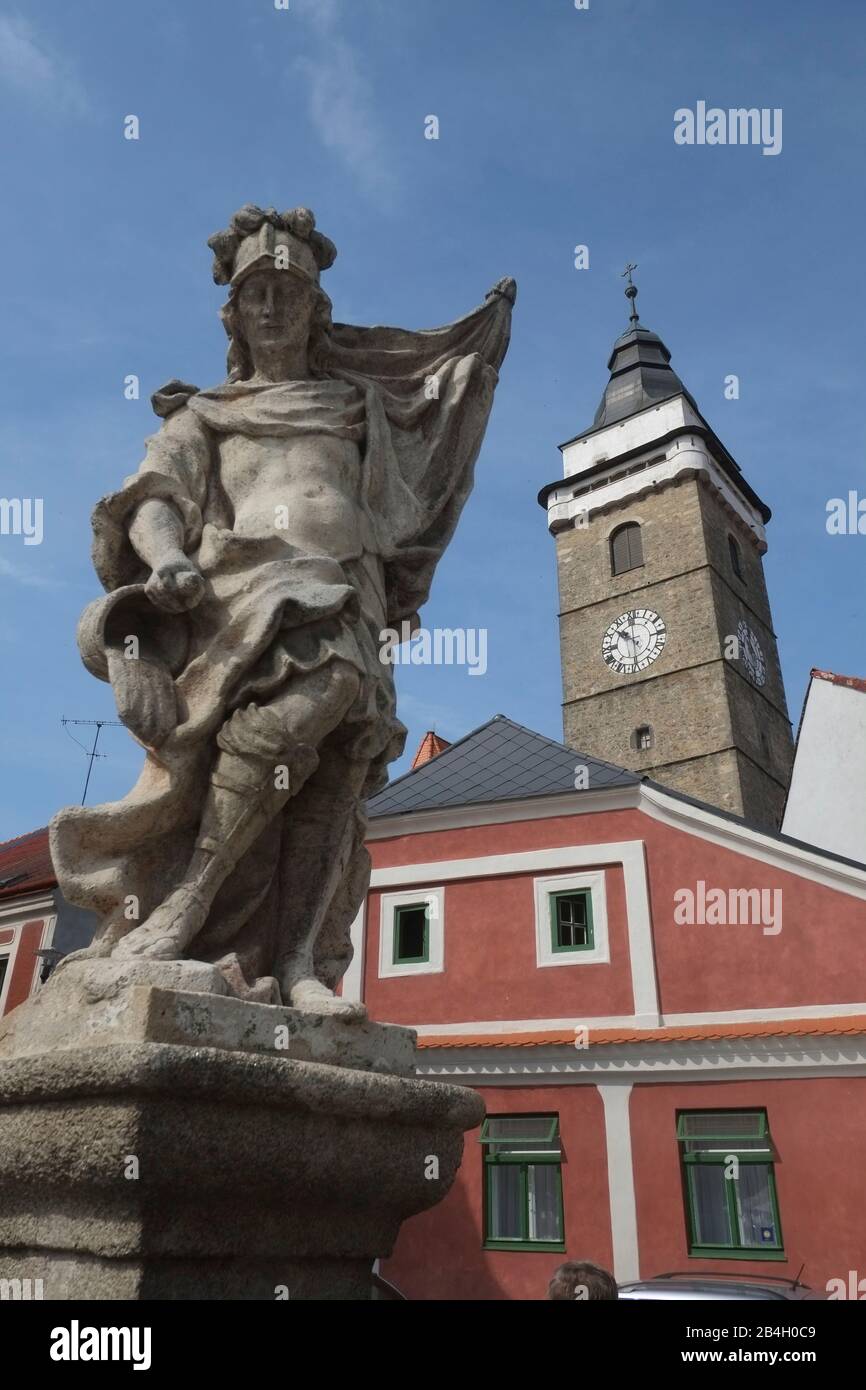 Slavonice, Tschechien. Stein-Barock-Brunnen mit Statue des heiligen Florian am oberen Platz mit Stadtturm 56 Meter hoch aus dem frühen 16. Jahrhundert Stockfoto