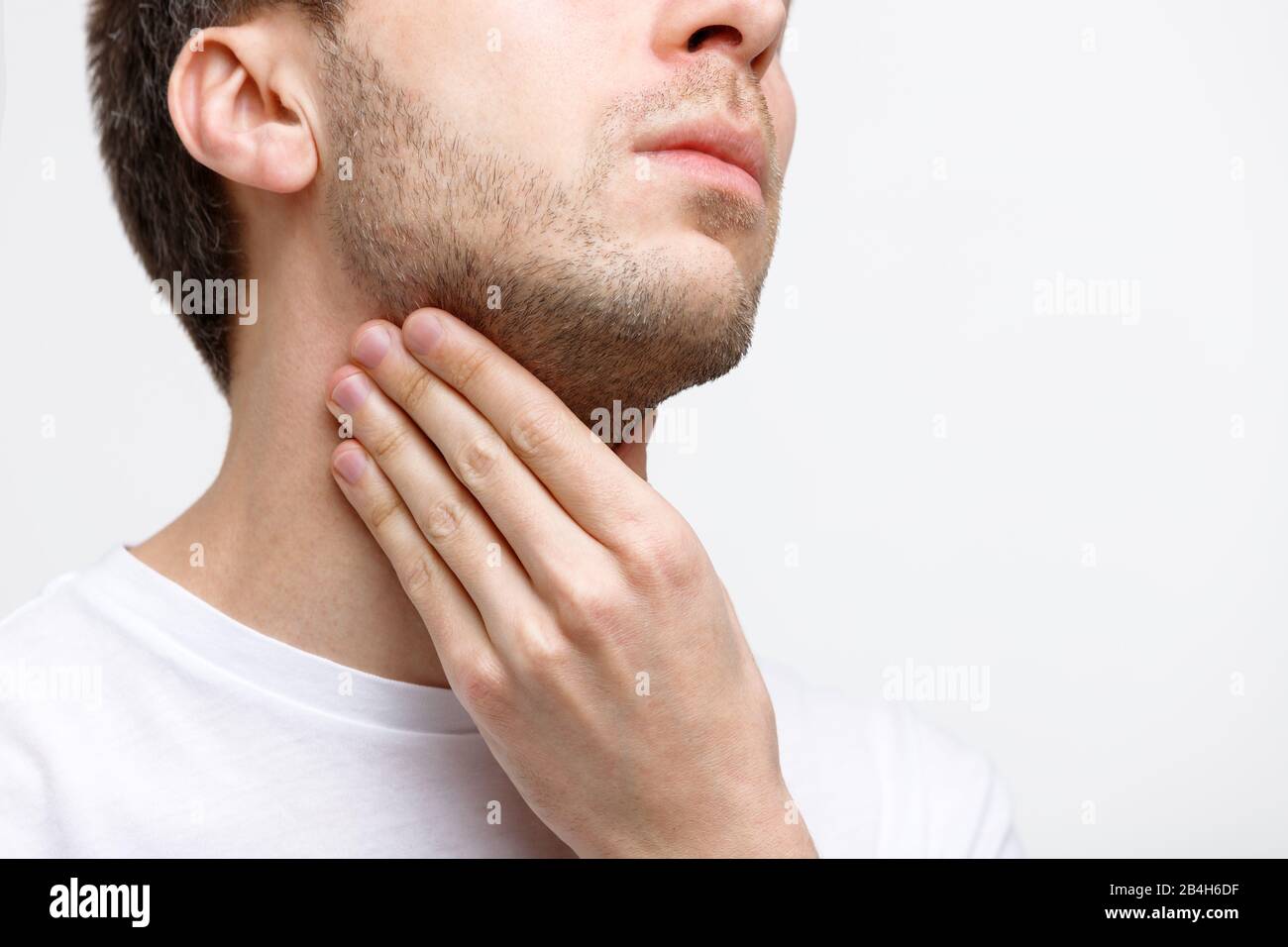 Nahaufnahme eines kranken Mannes, der an Kehlproblemen leidet, grauer Hintergrund, isoliert. Lymphdrüsen, schmerzhaftes Schlucken, Pharyngitis, Kehlkopfschwellkonz Stockfoto