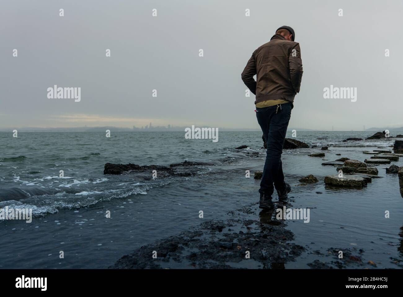 Man macht Trail über die Bucht mit Stadt Silhouette am Horizont Stockfoto