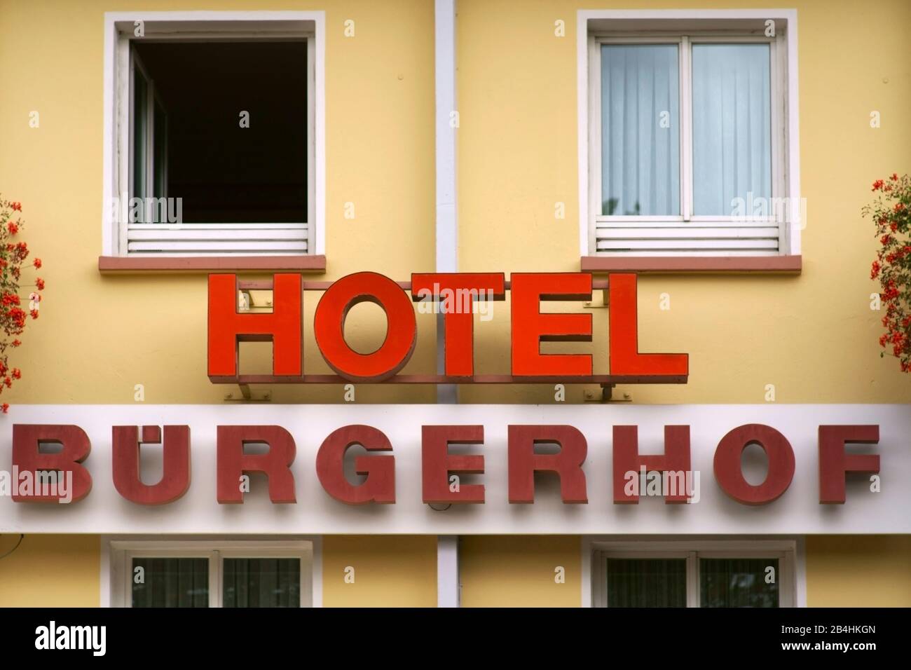 Das Hotelschild des Hotels Buergerhof mit gelber Fassade und Blumenschmuck in Homburg. Stockfoto