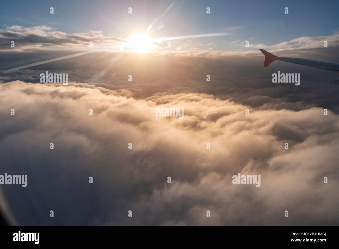 Blick aus dem Fenster eines Flugzeuges auf geschlossener Wolkendecke bei Sonnenuntergang Stockfoto