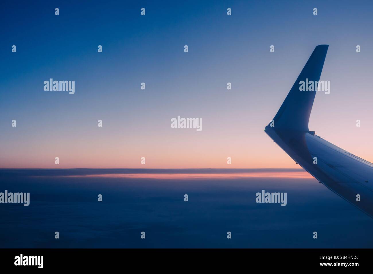 Flugzeugflügel mit Sonnenaufgang im hellen Licht durch das Flugzeugfenster mit weichem Fokus. Stockfoto